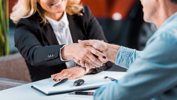 A buyer and seller shaking hands at a table.