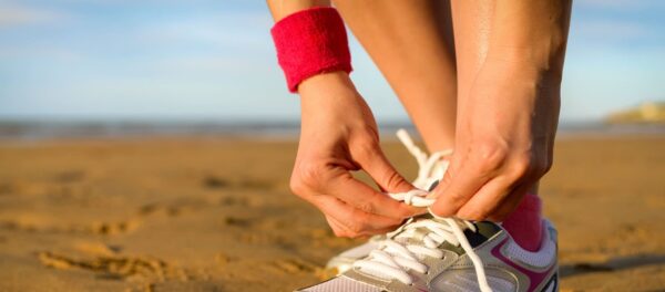A woman tying her shoes on the beach, captured by a talented photographer.